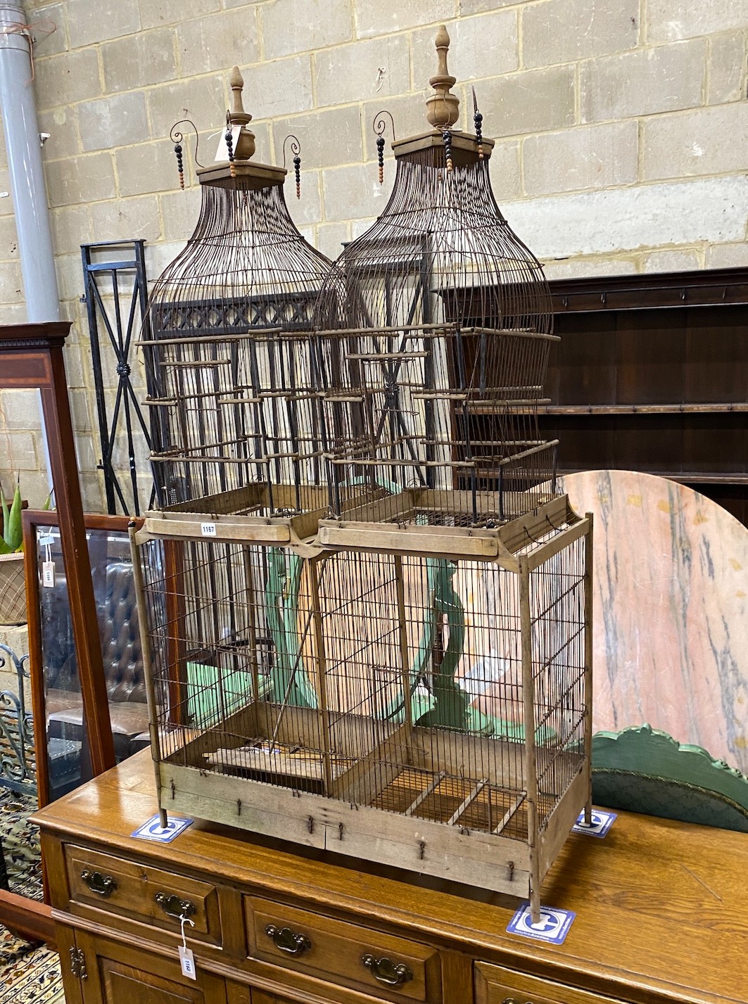 An early 20th century continental beech framed wire work bird cage of twin turret design with turned finials width 80cm depth 36cm height 146cm